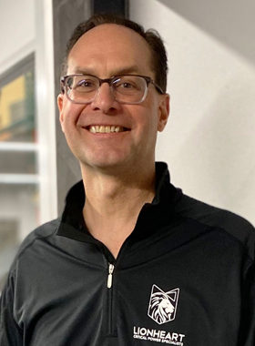 smiling employee in black quarter-zip lionheart sweater