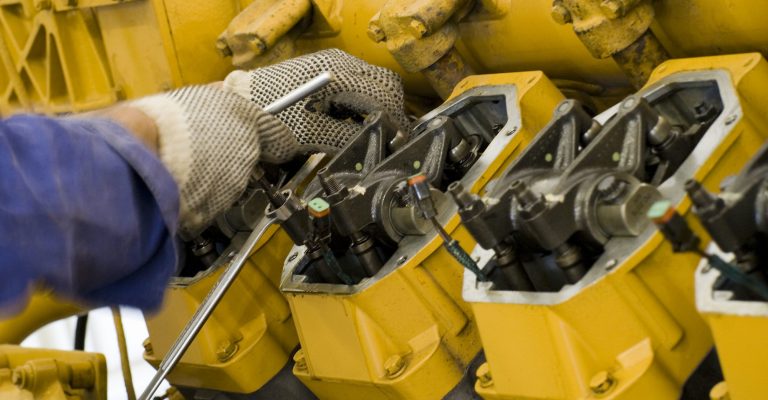 closeup of a gloved hand working on a yellow commercial generator